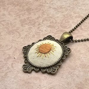 View of hand embroidered sunshine necklace showing details of bezel.