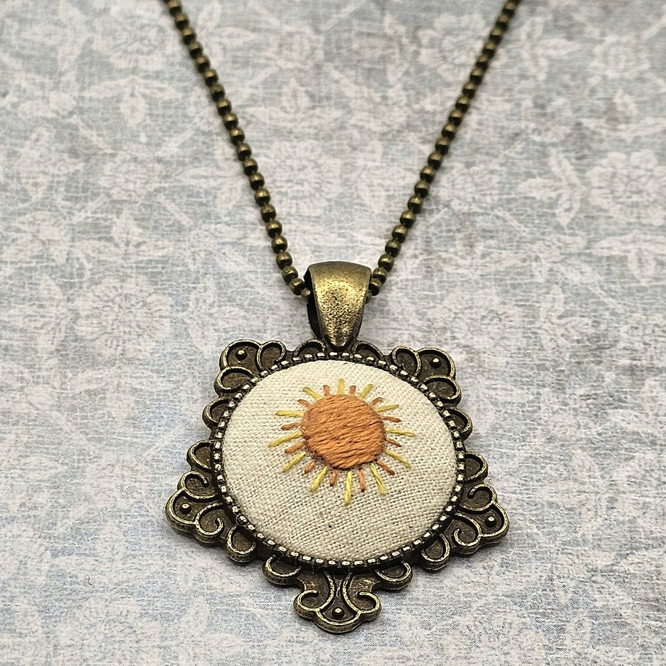 Angled view of hand embroidered sunshine necklace.